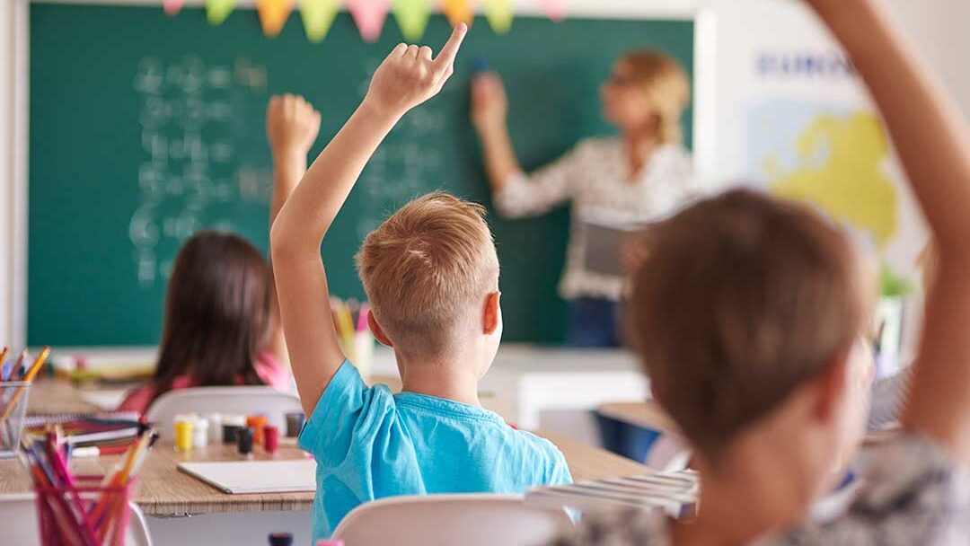 Niños levantando la mano en salon de clases